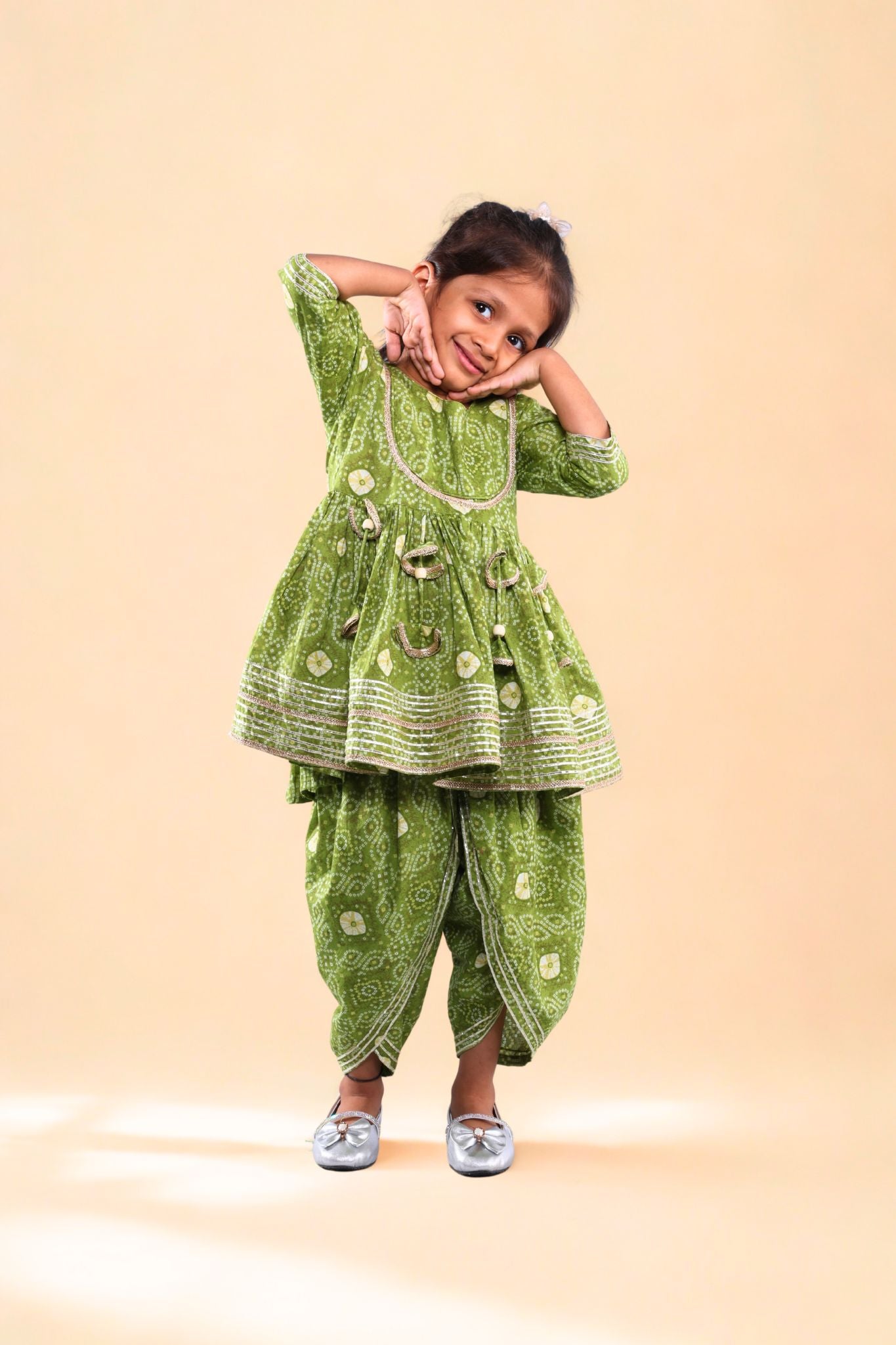 Child wearing a green traditional outfit on a beige background