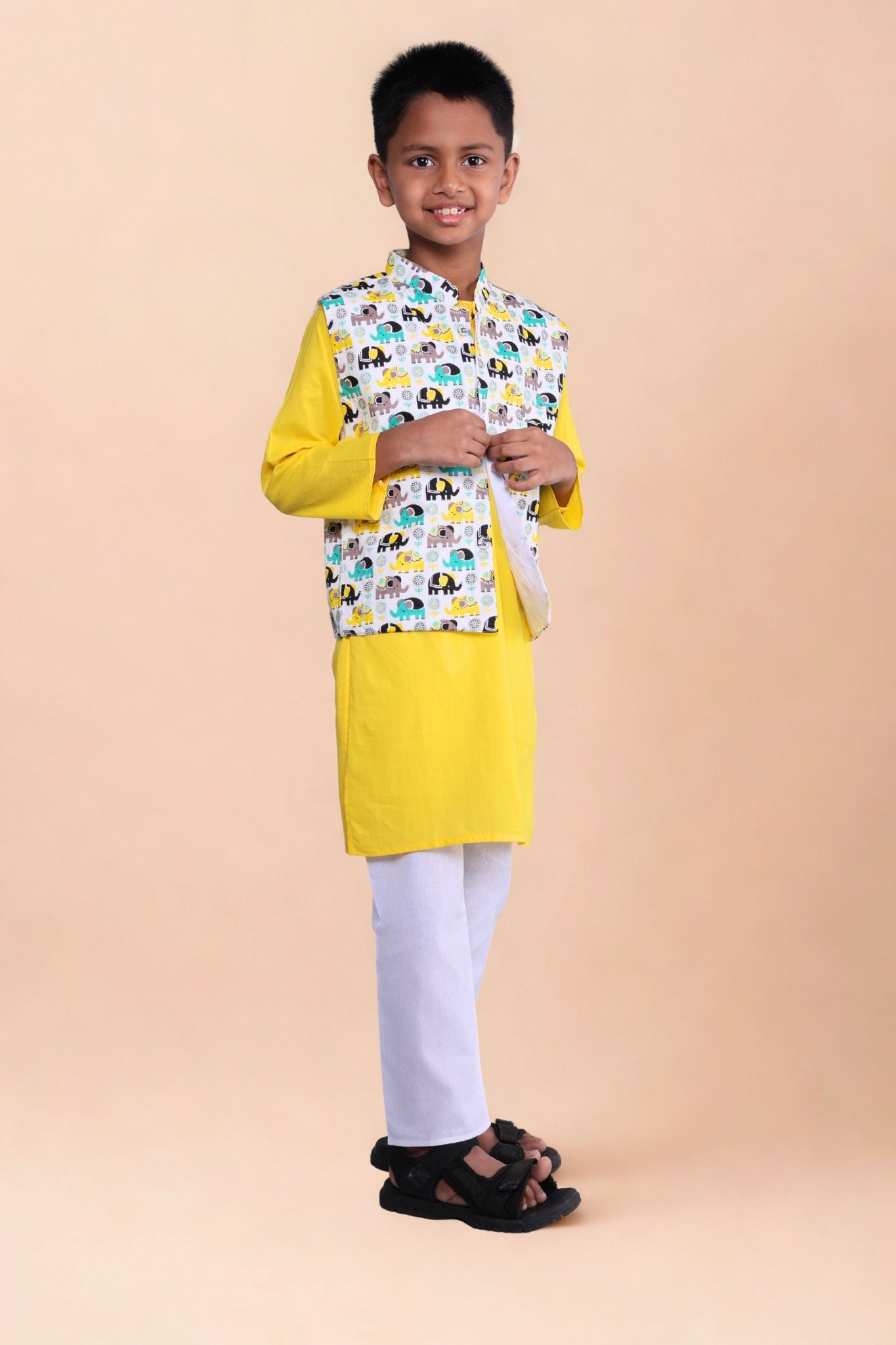 Child wearing a yellow kurta with a patterned jacket on a beige background