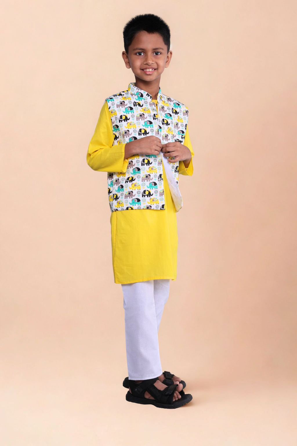 Child wearing a yellow kurta with a patterned jacket on a beige background